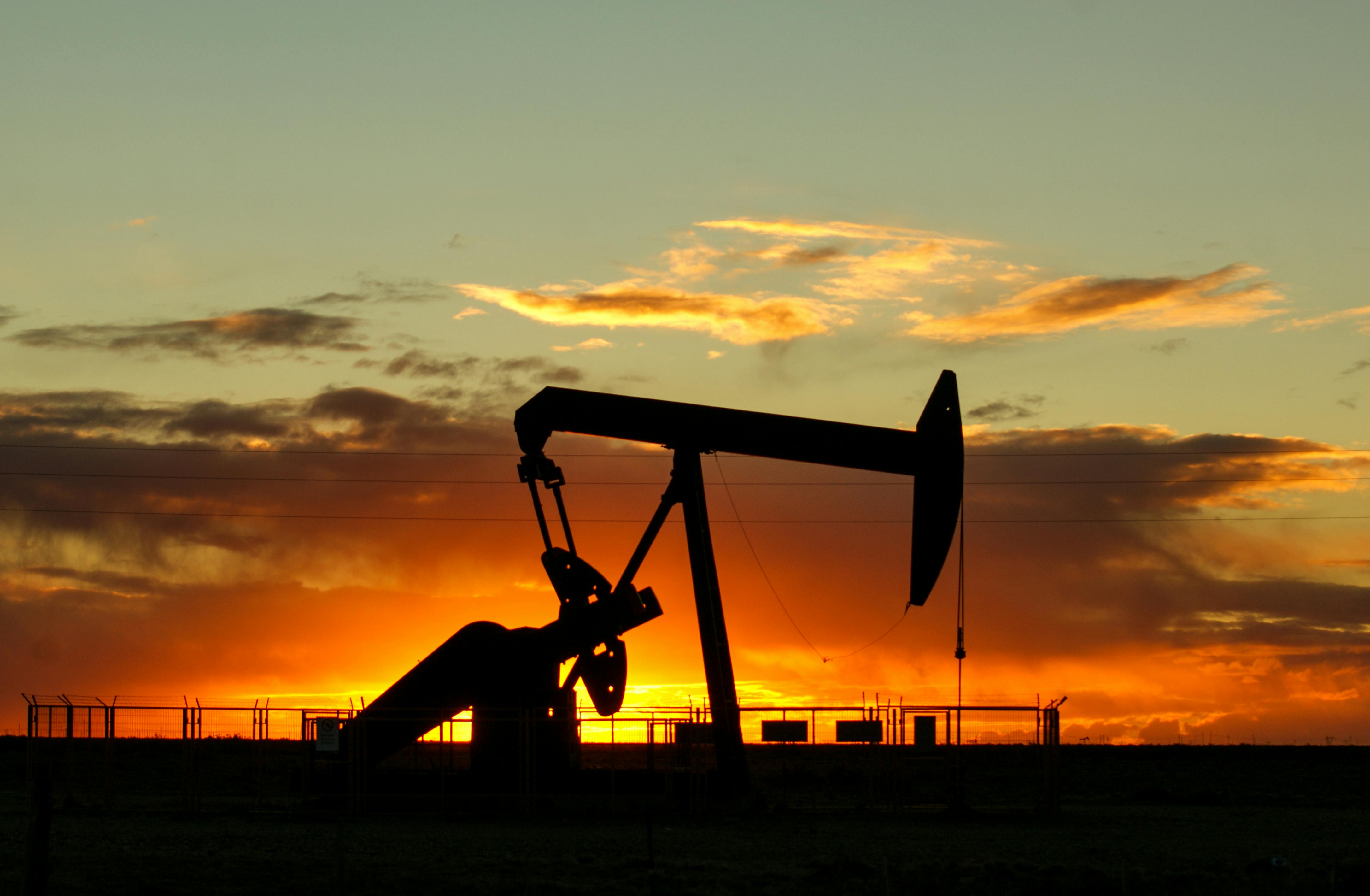 Oil pump silhouette at sunset — energy sector